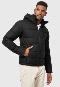 Schwarze Pufferjacke mit einem Reißverschluss vorne, Kapuze und seitlichen Taschen. Verfügt über ein gestepptes Design mit einer glatten, matten Textur.