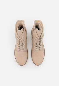 Bottines beiges en daim au texture lisse, avec des lacets, des zips sur le côté et de subtils accents dorés. Design à bout arrondi.