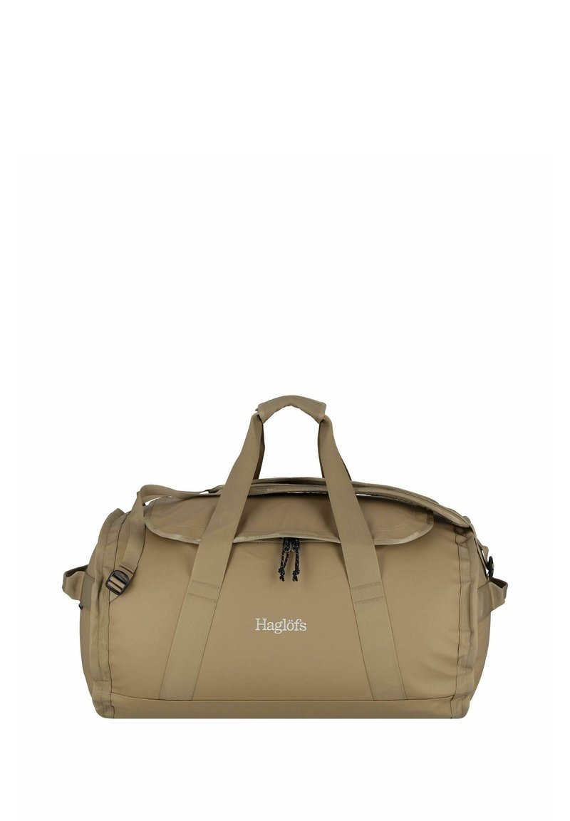 Bolso de viaje beige fabricado en tejido duradero, con doble asa, correa para el hombro y una parte superior con cremallera y detalle de cordón. Logotipo de Haglöfs visible.