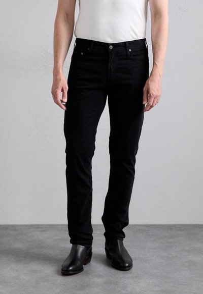 Czarne dżinsy o slim fit, z pięcioma kieszeniami, zapinane na guzik, o gładkiej fakturze, w komplecie z czarnymi skórzanymi botkami.