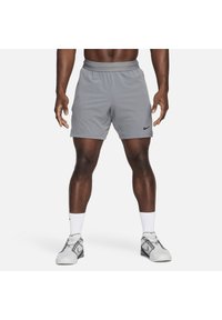 Bermudas atléticas grises con cinturilla elástica, que presentan un pequeño logo negro de Nike en el lateral. La tela parece ligera y transpirable.