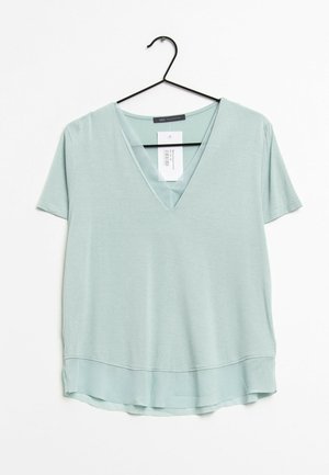 Mintgrünes T-Shirt mit kurzen Ärmeln und V-Ausschnitt, aus weichem Stoff gefertigt, mit abgerundetem Saum und einem Anhänger auf der Rückseite.
