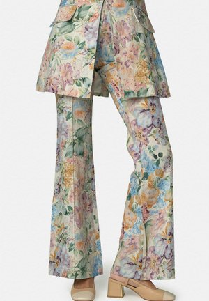 Pantalones de pierna ancha con estampado floral combinados con chaqueta larga a juego, zapatos de tacón bloque beige con punta cerrada y tira trasera.