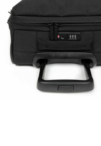 Černý kufr na kolečkách s odolným textilním povrchem, vyjímatelnou rukojetí a zámkem pro bezpečnost. Obsahuje zipovou kapsu a texturovaný povrch.