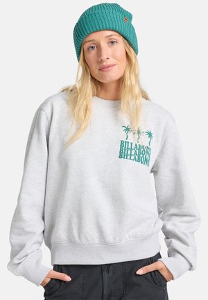 Grå sweatshirt med en grön palmträdsgrafik och "Billabong"-text. Kombinerad med en teal stickad mössa som visar en ribbad textur.