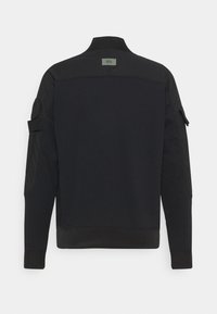 Černá mikina s vysokým límcem, dlouhými rukávy a žebrovanými manžetami. Na levém rukávu je našitá kapsa a na zádech je etiketa.