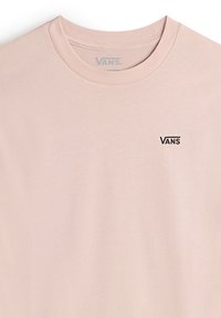 Maglietta rosa chiaro in morbido cotone, con collo rotondo e un piccolo logo nero "VANS" sulla parte superiore sinistra.