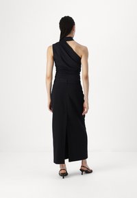 Robe noire asymétrique avec un buste froncé, jupe longue et fente haute. Fabriquée en tissu lisse, avec une taille cintrée et un design minimaliste.