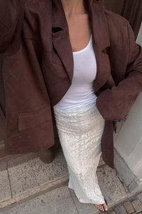 Brun ruskinds oversized blazer, hvid tank top, tekstureret hvid nederdel med blomstermotiv, sorte flip-flops; detaljeret syning på nederdelen.