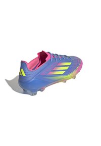 Blue soccer cleat with pink accents, featuring a sleek design, textured synthetic upper, and transparent studs for traction.