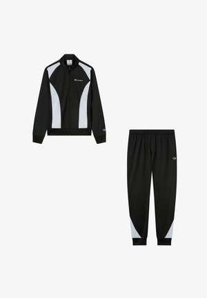 Black and white Champion tracksuit set with zip-up jacket featuring white side panels and matching black pants with white accents at the calves.
