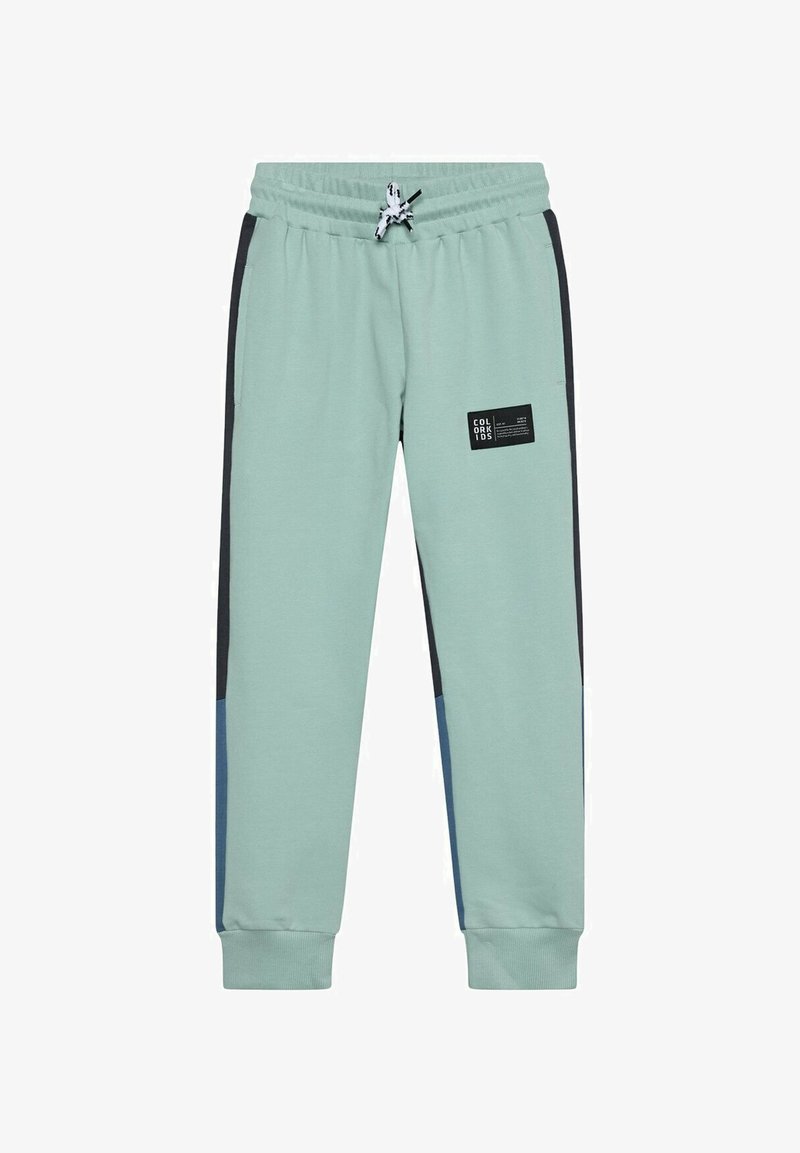 Pantalon de jogging vert clair avec taille élastique, bandes noires sur les côtés, patches bleus près des poignets, et un petit patch logo noir sur la cuisse droite.
