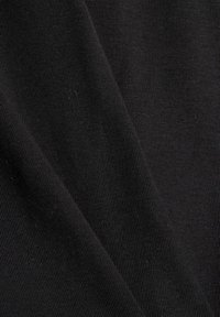 Gros plan d’un tissu côtelé noir plié montrant une fine texture verticale et une qualité de matériau souple.