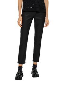 Czarne dopasowane spodnie wykonane z gładkiego materiału, o klasycznym kroju i długości do kostek. W połączeniu z błyszczącymi czarnymi loafersami i strukturalnymi skarpetkami.