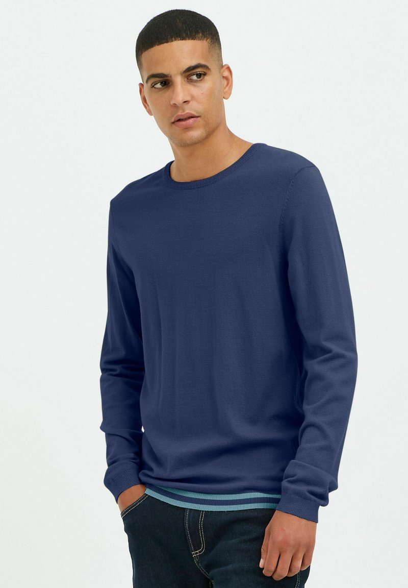 Navy zils garām piedurknēm džemperis, izgatavots no mīksta auduma, ar apaļu kaklu un teksturētām piedurknēm, pārklāts ar tirkīza svītrainu apakšmalu.