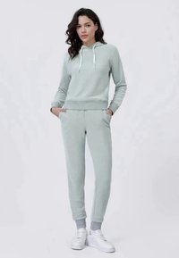 Trening din terry cloth moale, de culoare verde deschis, cu glugă, cu manșete ribbate și buzunare; prezintă o textură subtilă și accente gri asortate.