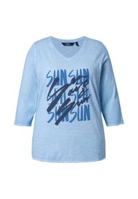 Chemise bleu clair à col en V avec manches trois-quarts, présentant le texte bleu foncé "SUN" répété et une superposition de script en gras.