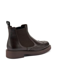 Stivaletti in pelle marrone con pannelli elastici ai lati, punta rotonda, dettagli brogue e una spessa suola in gomma marrone. Linguetta sul retro per una facile calzata.
