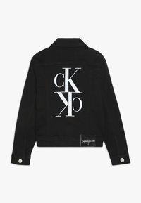 Schwarze Jeansjacke mit großem weißen CK-Logo auf dem Rücken, mit Knopfverschlüssen und einem gewebten Etikett am Saum. Klassischer Kragen und Manschetten.