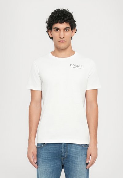 T-shirt en coton blanc à manches courtes, col rond, avec le logo "DONdup" sur la poitrine gauche. Porté avec un jeans en denim bleu clair.