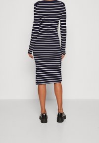 Navy och vit randig ribbad stickad klänning, långa ärmar, figurnära silhuett, midi längd, bärs med klumpiga svarta plattformsskor.