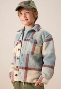 Veste en polaire à carreaux bleu clair et crème avec des boutons marron et une poche poitrine. Manches longues avec poignets à boutons, design décontracté.