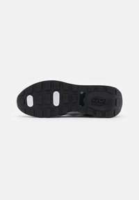 Black rubber shoe sole with textured pattern, featuring rectangular lugs and circular cutouts for traction and flexibility.