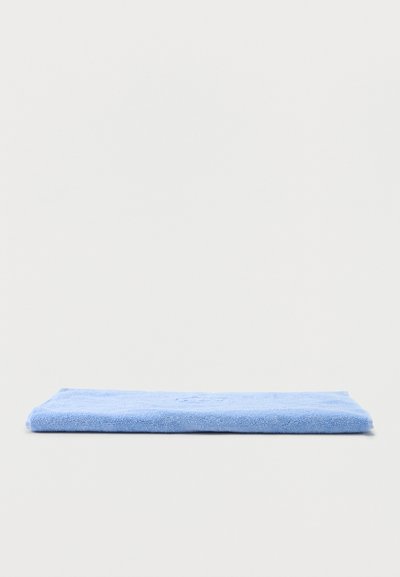 Svetlo modra mikrovlakenska krpa, lepo zložena na preprosti beli površini, prikazuje teksturo in robove.