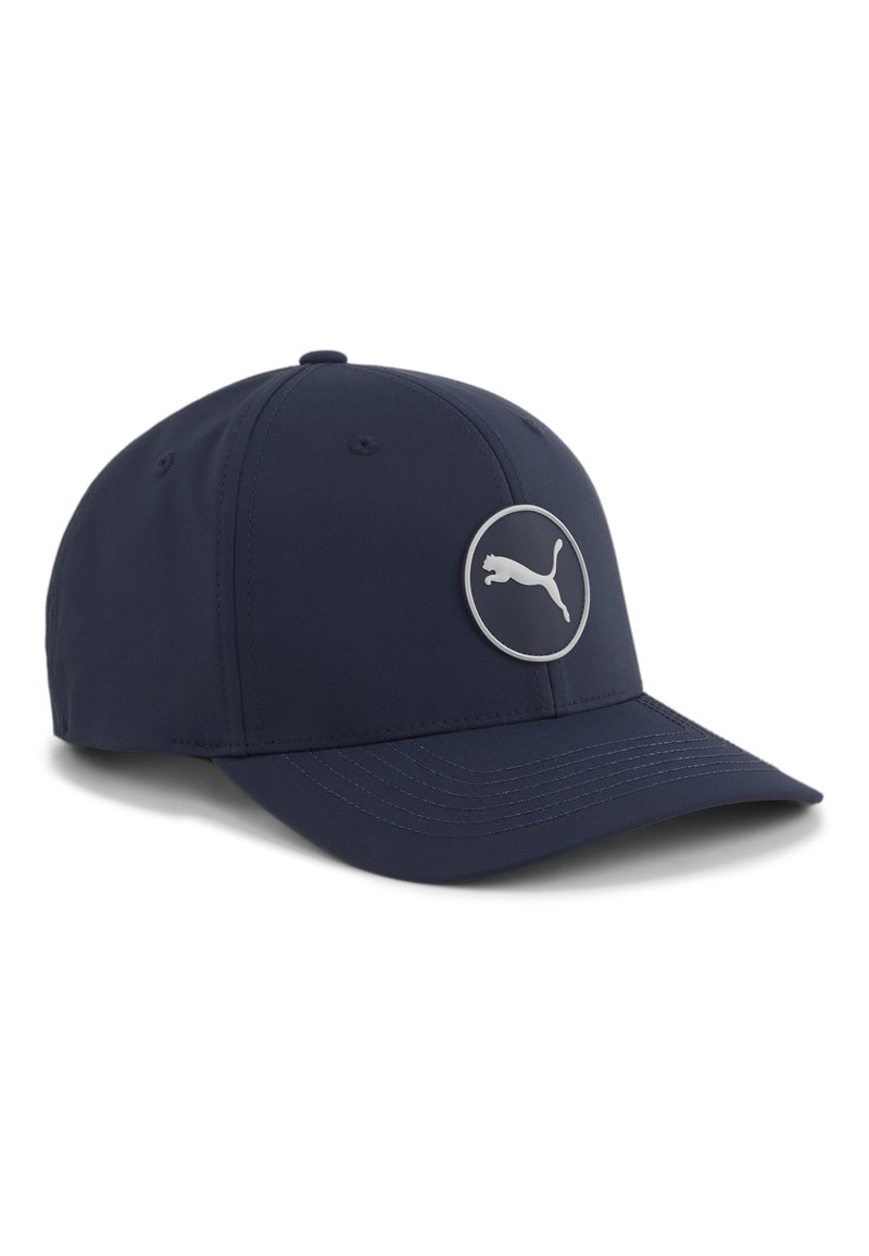 Gorra de béisbol azul marino con visera curva y parche redondo del logo de Puma en el panel frontal, con detalles de costura visibles en la visera.