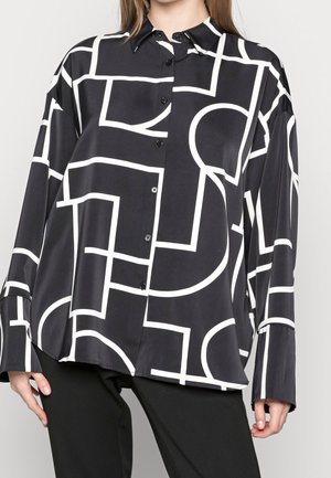 Schwarze Bluse mit weißen geometrischen Mustern, mit durchgehender Knopfleiste, langen Ärmeln und einer glatten, glänzenden Stoffstruktur.