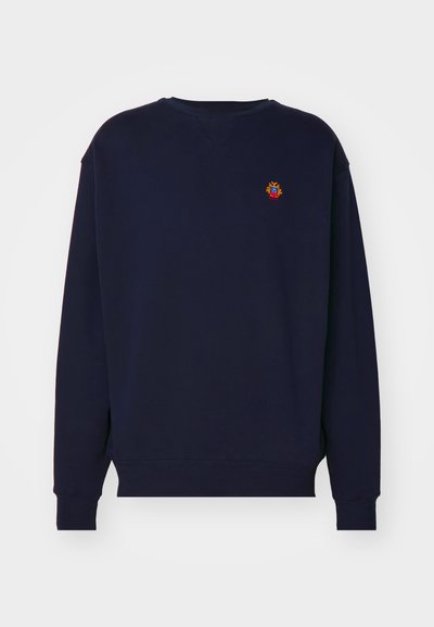 Navy blue sweatshirt with a round neckline, long sleeves, and ribbed cuffs. Features a small embroidered design on the chest.