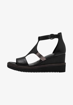 Black wedge sandal featuring a smooth leather upper, open toe, ankle strap with a buckle, and decorative metallic accents. Textured sole.