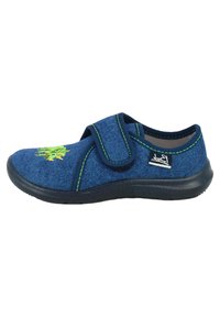 Chaussure en denim bleu avec une sangle Velcro, des coutures vertes et une semelle texturée. Elle présente un motif brodé vert sur le bout.