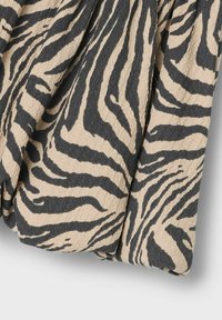 Bež šal iz blaga z teksturirano površino, ki ima drzen črni zebra vzorec. Material izgleda mehak in se lepo prilega.