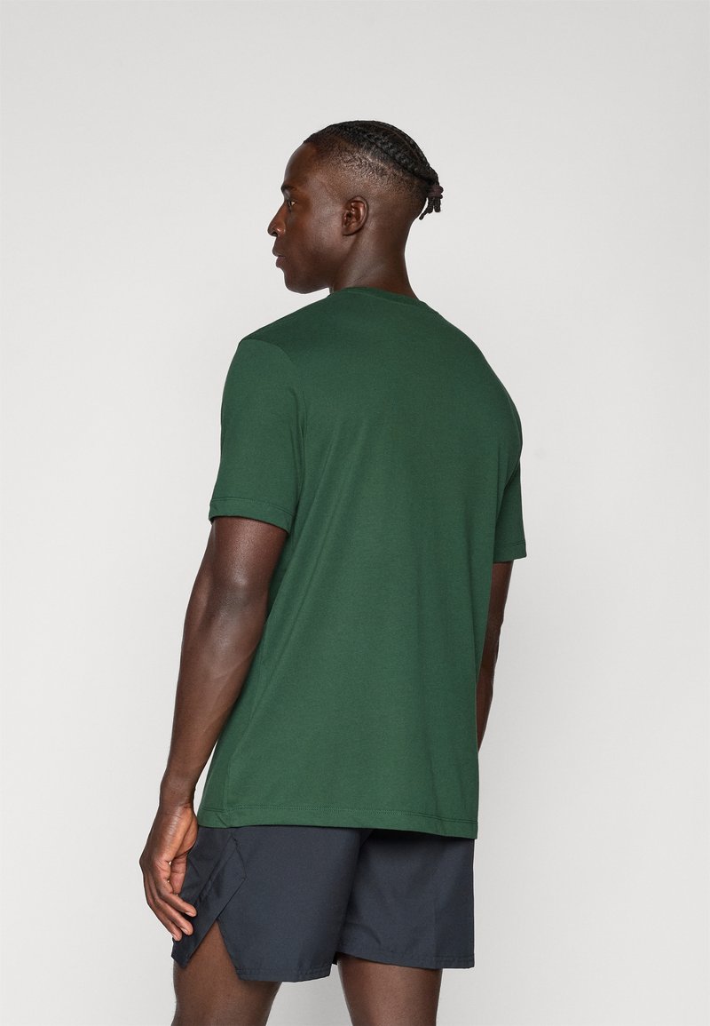 Mørkegrøn t-shirt med korte ærmer og rund hals. Stoffet ser glat ud, og pasformen er afslappet. Bæres med sorte sports-shorts.