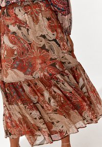 Lange, gestufte Rock mit Paisley- und Blumenmustern in Rot, Braun und Creme. Hergestellt aus leichtem, durchscheinendem Stoff mit einem fließenden Design.