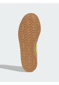 Podeszwa buta z teksturowanym, falistym wzorem z gumy w jasnobrązowym kolorze, z subtelnym logo i zakrzywionym kształtem wzdłuż krawędzi.