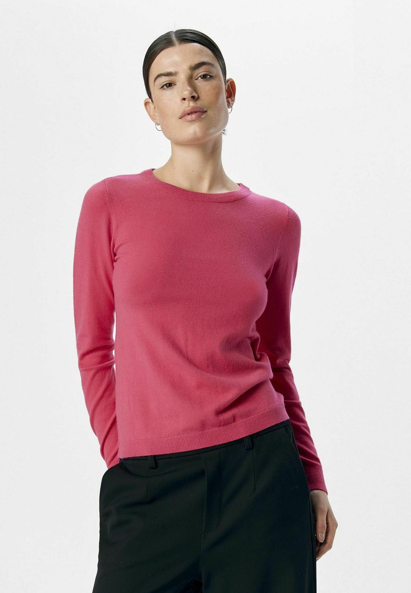 Suéter ajustado de manga larga en un vibrante color rosa, hecho de un material de punto suave. Cuello redondo con ribetes en los puños y el dobladillo.
