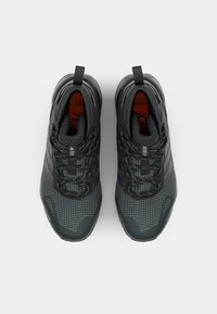 Graue Performance-Schuhe mit einem strukturierten Mesh-Obermaterial, Akzenten in Gittermuster und verstärktem Fersenbereich, ausgestattet mit einem Schnellziehverschluss und Zugschlaufen.