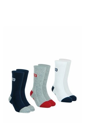 Trois paires de chaussettes montantes : bleu marine avec des orteils gris, gris avec des orteils rouges et blanc avec des orteils bleu marine. La texture du tissu est côtelée, avec des accents de logo.