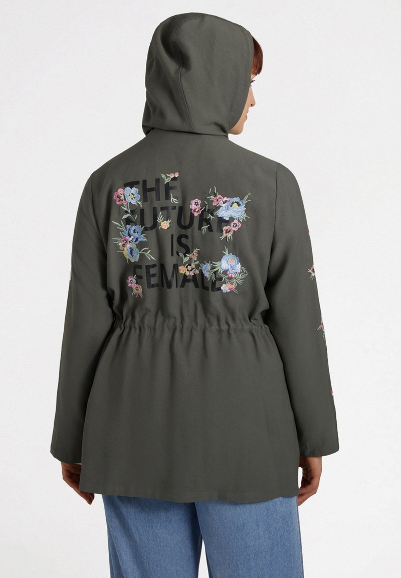 Grön huva jacka med blommönsterbroderi och text på baksidan. Elastisk midja, långa ärmar och en avslappnad passform. Avslappnad design.