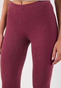 Bordo tajice napravljene od mekanog, teksturiranog materijala. Prilagođen dizajn s elastičnom waistband-om, vidljivim šavnim detaljima i bešavnom završnom obradom.