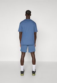 Blue cotton t-shirt and shorts set, relaxed fit, short sleeves, back view, paired with black sneakers and white socks.