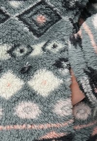 Fleece deka s geometrickým vzorom v odtieňoch sivej, bielej a jemne ružovej s plyšovým, textúrovaným povrchom.