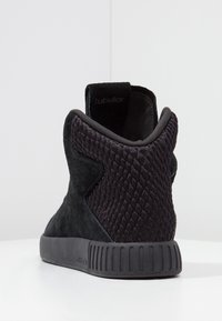 Černá atletická bota s texturovaným svrškem skládajícím se z kombinace semiše a síťoviny. Tlustá gumová podrážka s drážkovanými akcenty, navržena pro pohodlí.