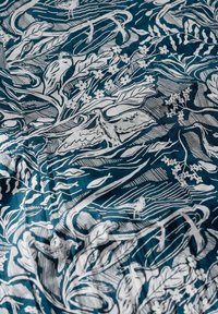 Tissu arborant un fond teal avec des illustrations botaniques blanches, incluant des oiseaux et des fleurs, offrant un design texturé et décoré.