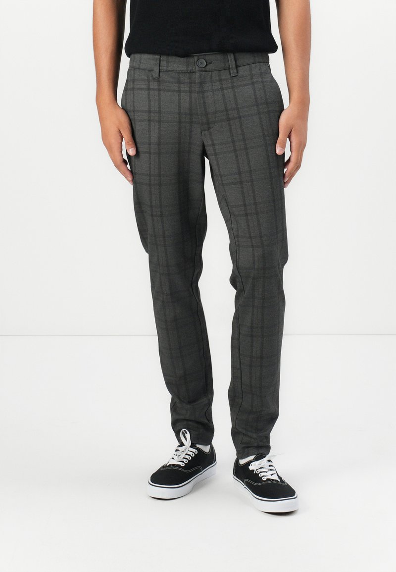 Grau karierte Hose aus gewebtem Stoff, mit schlanker Passform, flachem Frontdesign und Gürtelschlaufen, kombiniert mit schwarzen Sneakers.