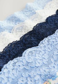 Kantstof met afwisselende strepen van lichtblauw, wit en marineblauw, met ingewikkelde bloemmotieven en golvende randen.