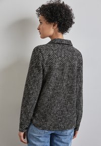 Svart- och vitrutigt skjortjacka med krage, långa ärmar och avslappnad passform. Texturerad tyg med rutigt mönster.