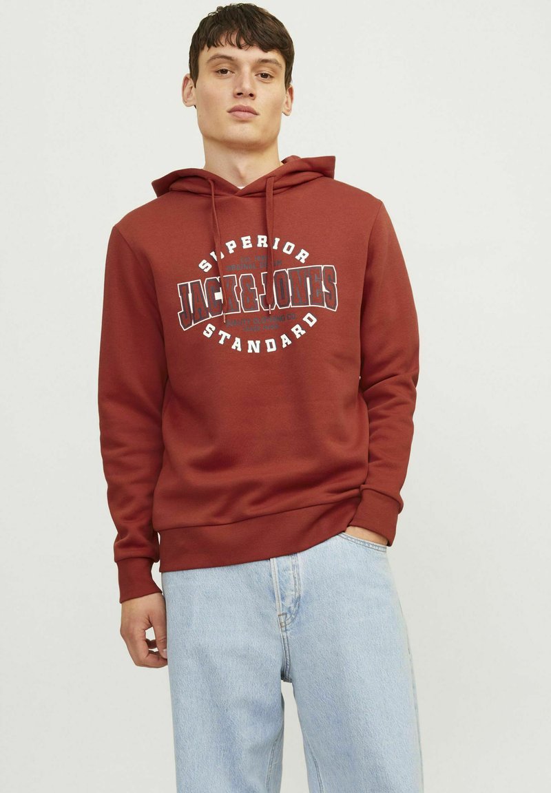 Burgunderfarvet hoodie med grafisk print på fronten, snøre i hætten, ribbede manchetter og kant. Sammen med lyseblå denim jeans.